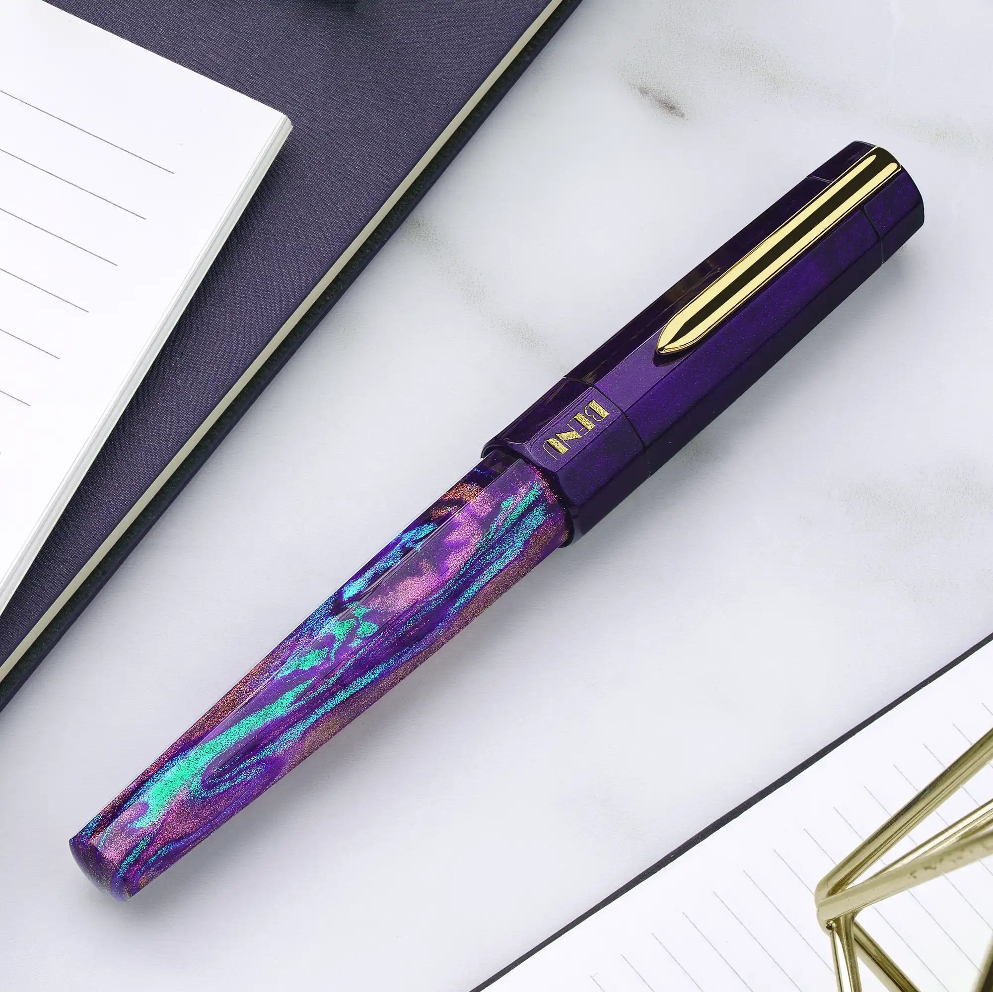 Benu Euphoria Opera Füllfederhalter aus lila prismatischem Resin mit Pflaume, Smaragdgrün und Magenta-Reflexen sowie vergoldetem Clip und Feder