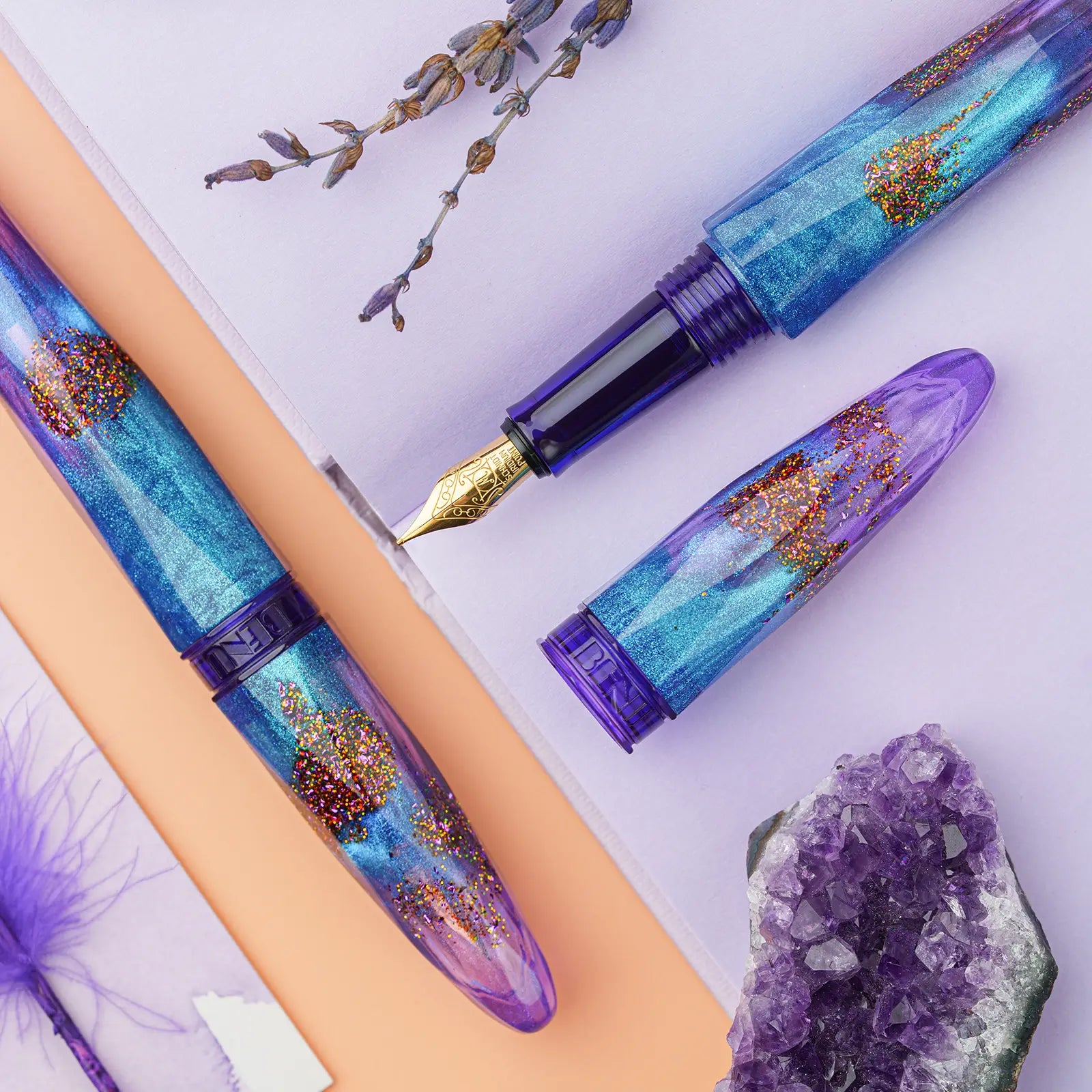 Benu Briolette Amethyst Tide Füllfederhalter aus lila-blauem Resin mit goldenen Glitzerakzenten und facettierter Oberfläche