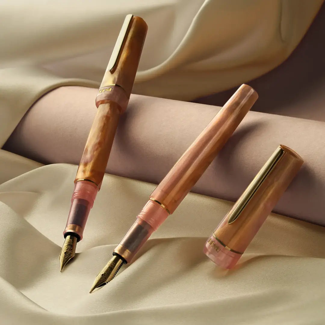 Benu Haute Lustre Füllfederhalter aus amber- und blushfarbenem Resin mit warmen Farbwirbeln, facettiertem Korpus und vergoldeter Feder
