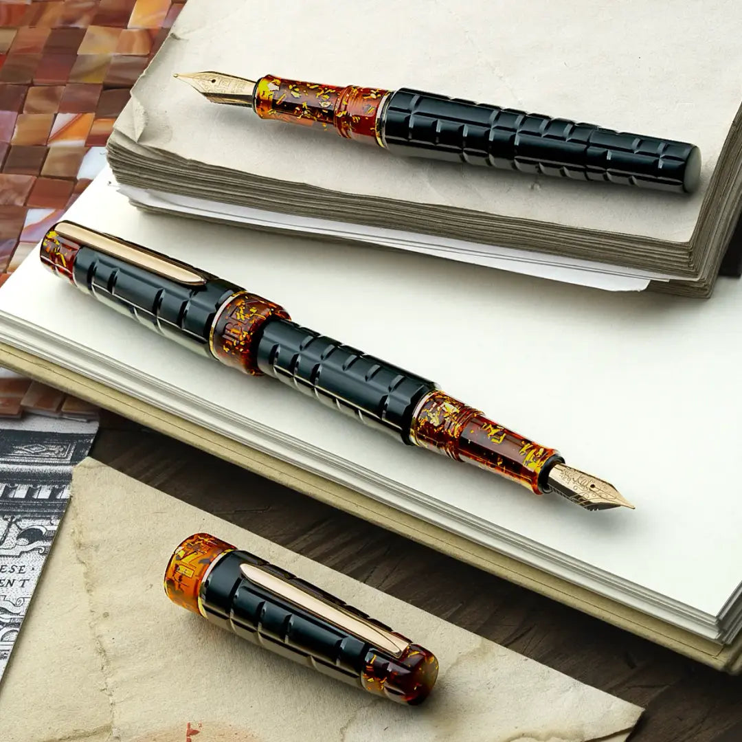 
Benu Tessera Black Amber Füllfederhalter aus mattem schwarz-ambernem Resin mit glänzenden Innenfacetten im Mosaik-Tessera-Design und vergoldetem Clip